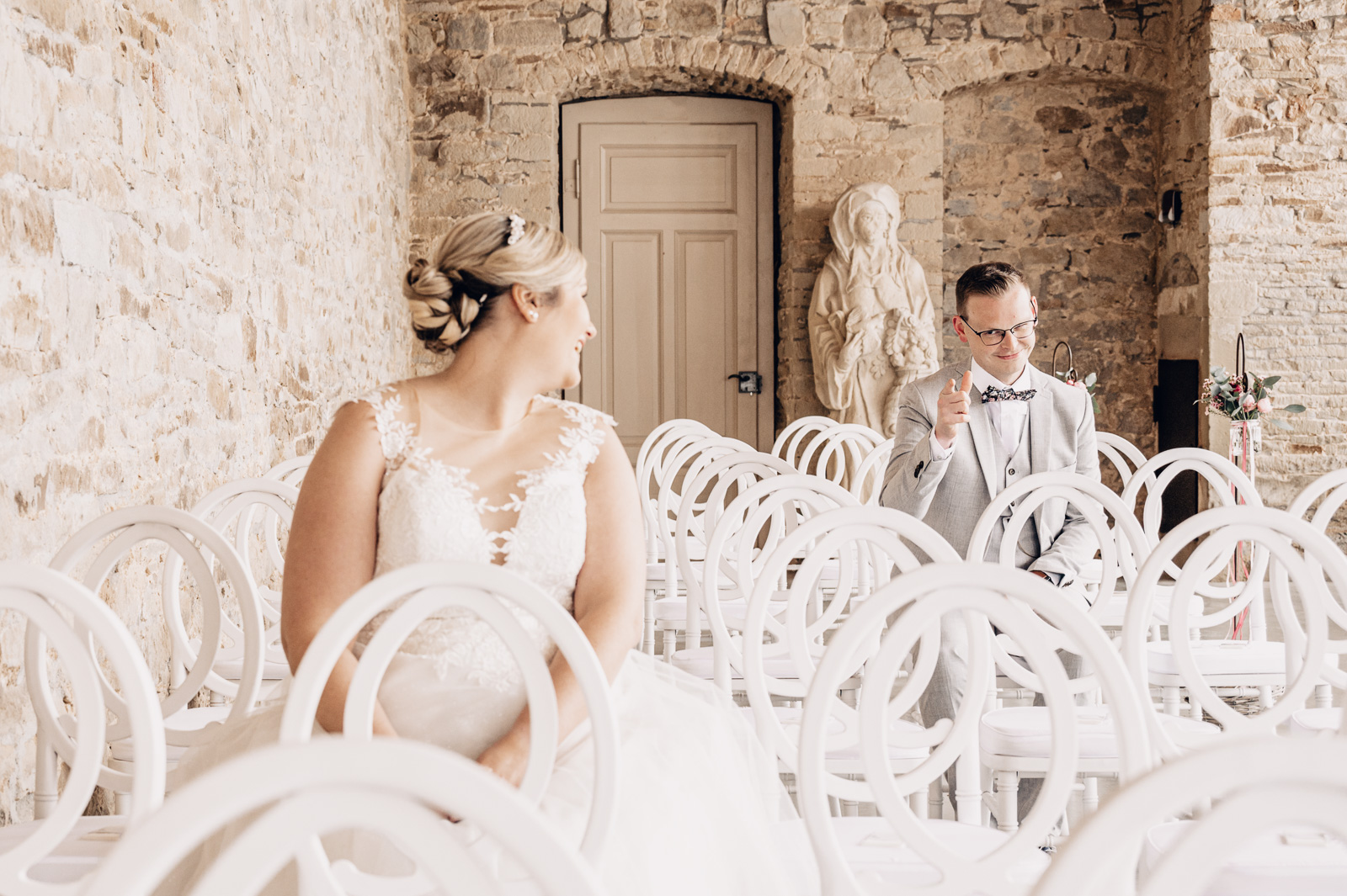 Brautpaar sitzt perspektivisch versetzt auf weißen Stühlen bei einer Hochzeit in Melle