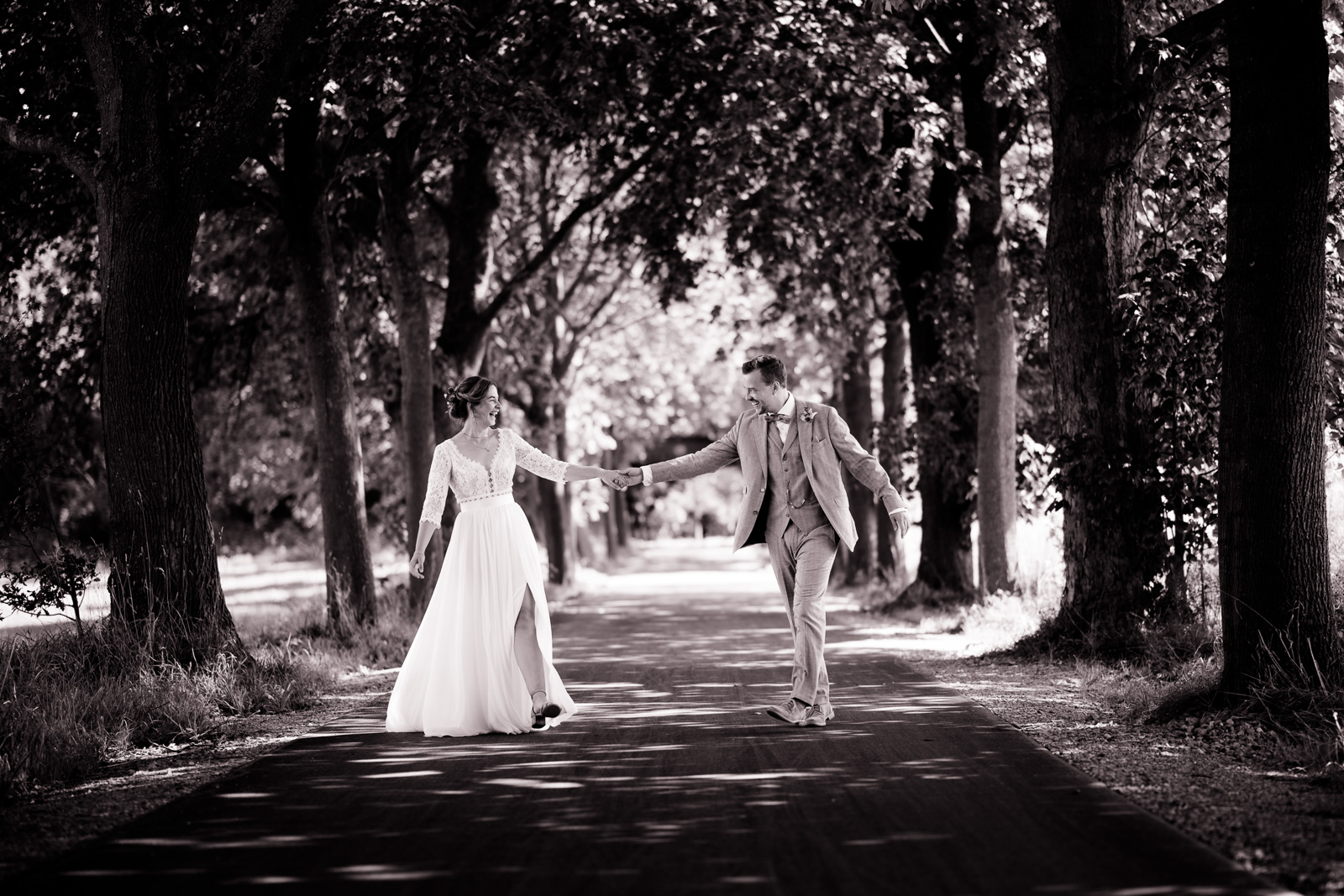 Paar läuft ausgelassen eine Allee entlang in Münster