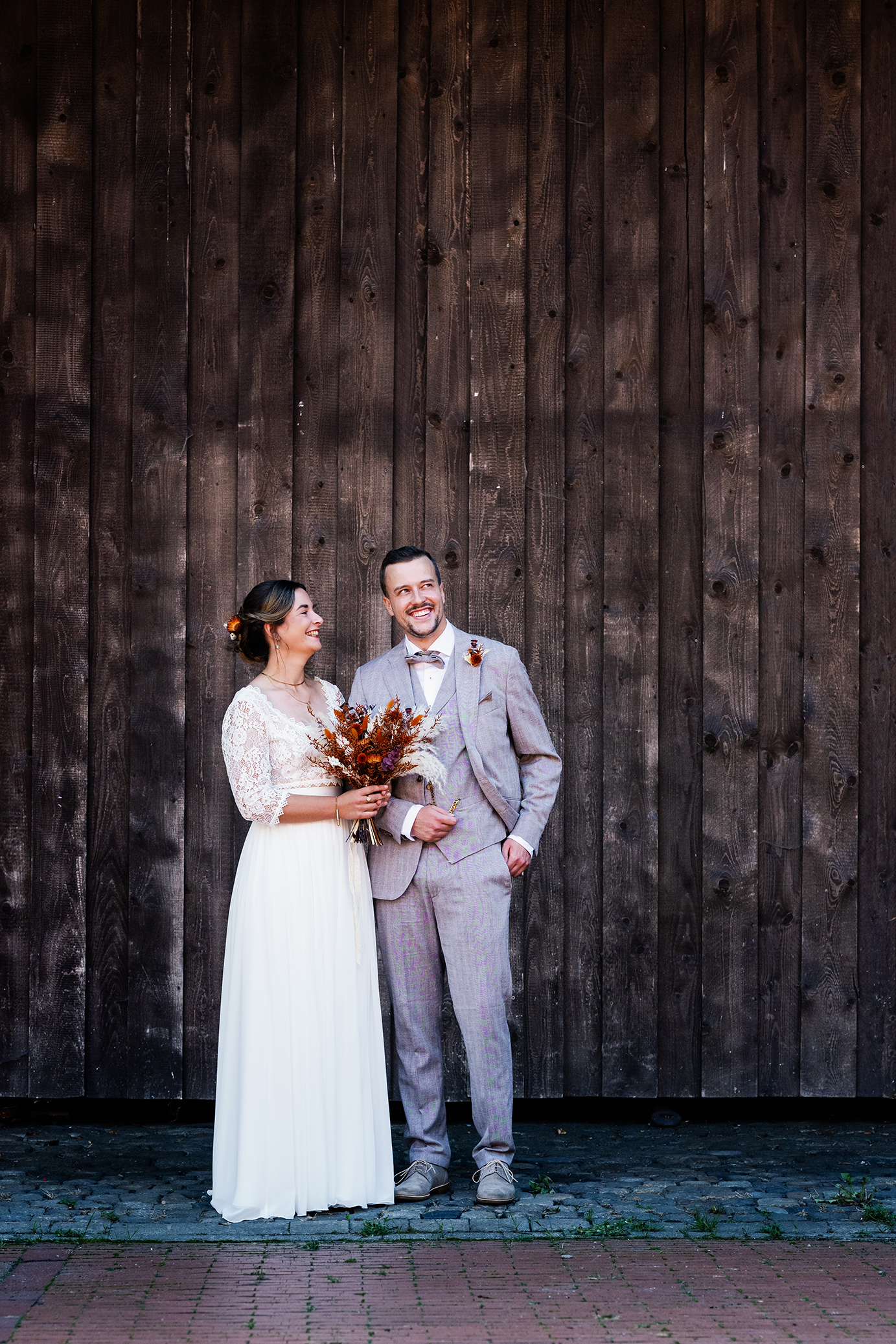 Brautpaar lachend vor einem großen Scheunentor in Münster
