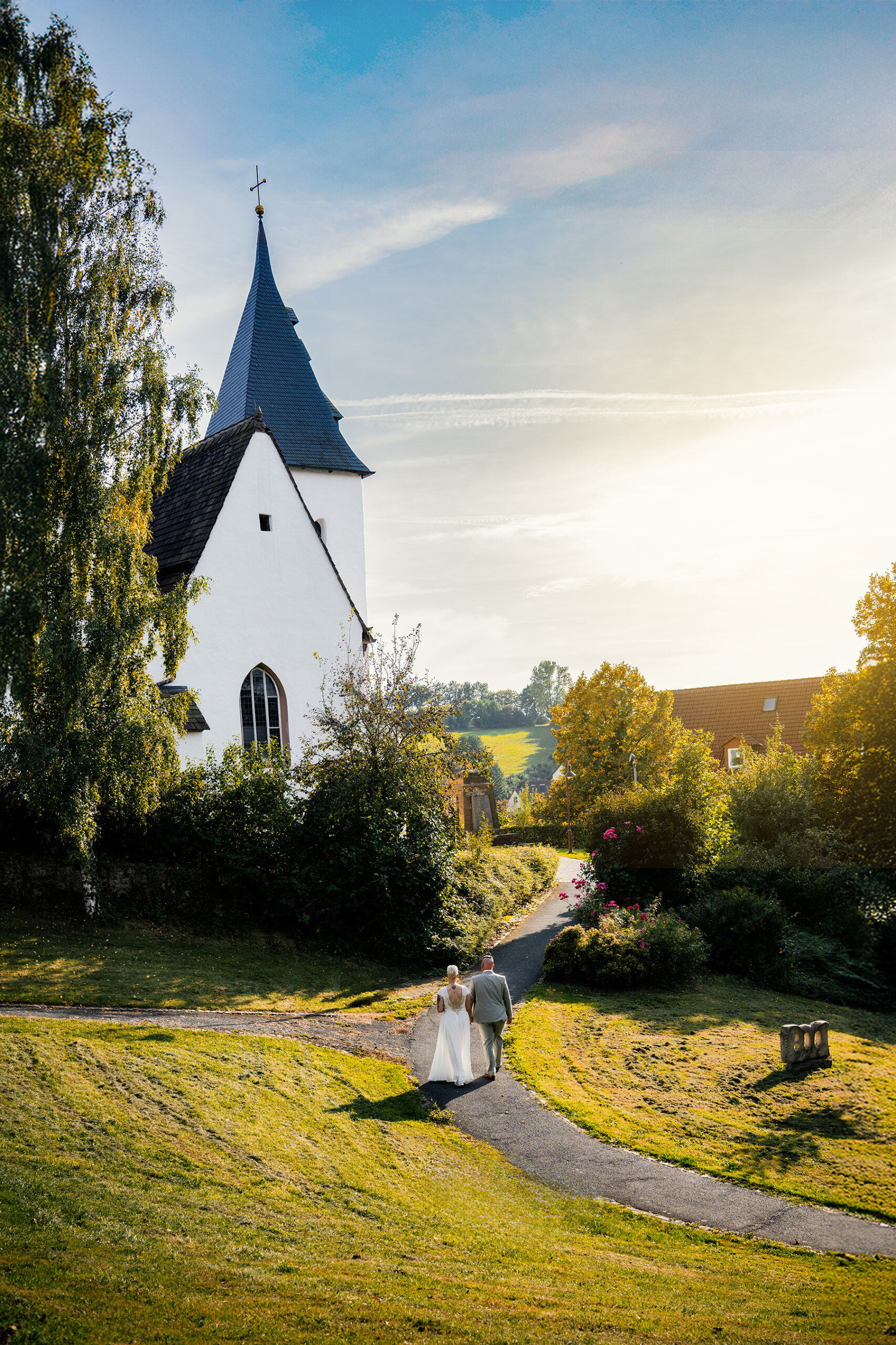 Brautpaar vor Kirche im Sonnenuntergang aus erhöhter Perspektive im Kalletal
